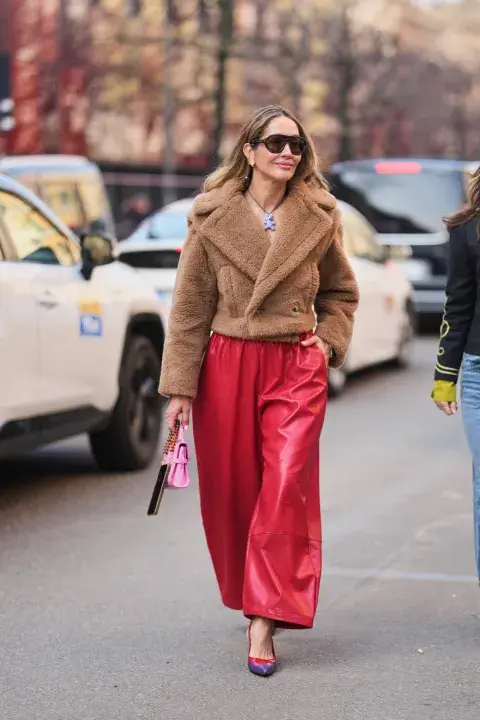 Una mujer con campera de corderito en color marron con un pantalón en color rojo Una mujer con campera de corderito en color marron con un pantalón en color rojo