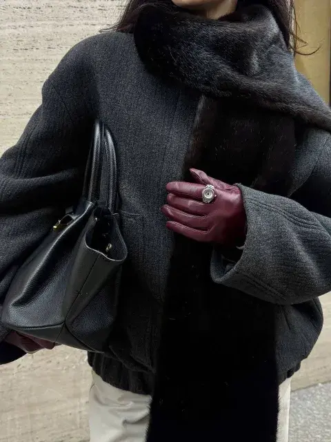 Una mujer sosteniendo su cartera con guantes en color borgoña Una mujer sosteniendo su cartera con guantes en color borgoña