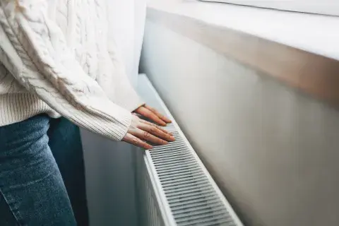 Foto de manos de una mujer sobre un calefactor en invierno.