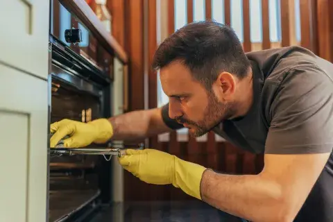 Un hombre limpiando el horno Un hombre limpiando el horno