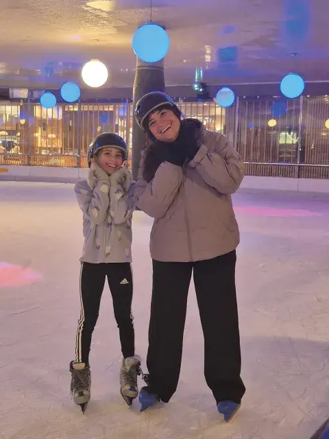 Una mujer y una niña en una pista de patinaje.