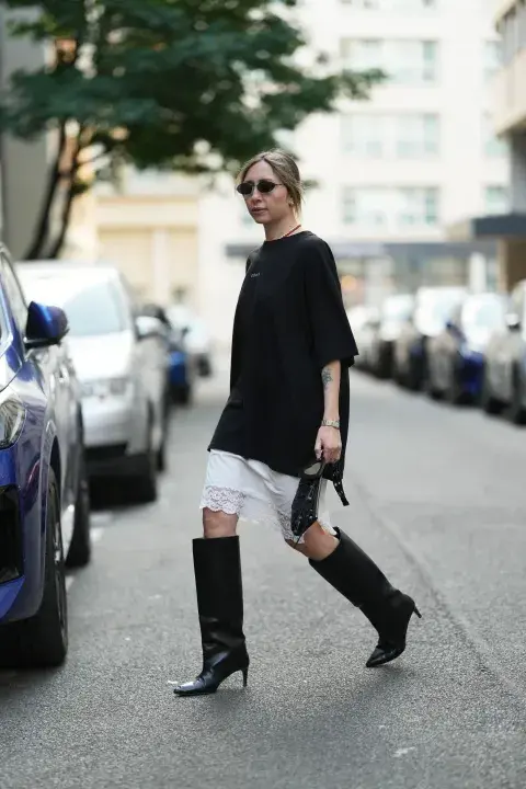Una mujer con un vestido corto y un remerón negro por encima. Le suma al outfit unas botas xl Una mujer con un vestido corto y un remerón negro por encima. Le suma al outfit unas botas xl