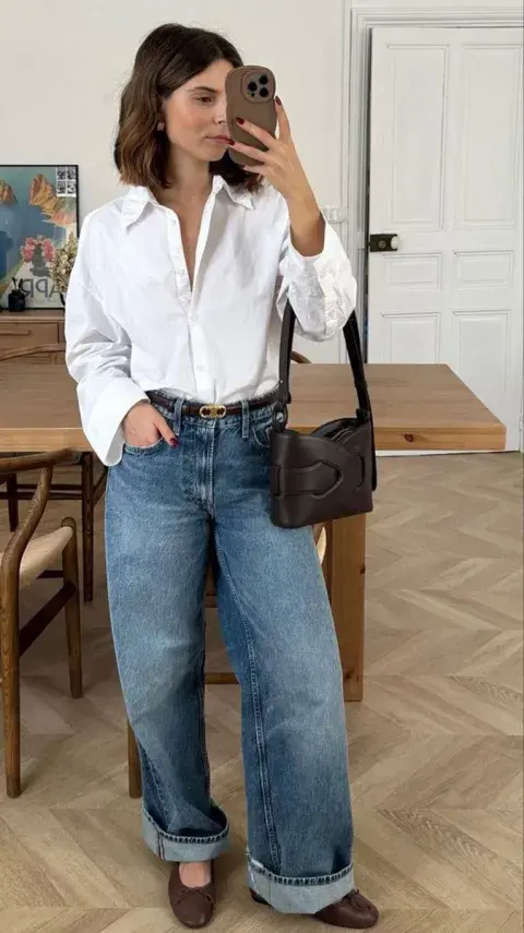Una mujer con un look sencillo con una camisa blanca y un jean Una mujer con un look sencillo con una camisa blanca y un jean