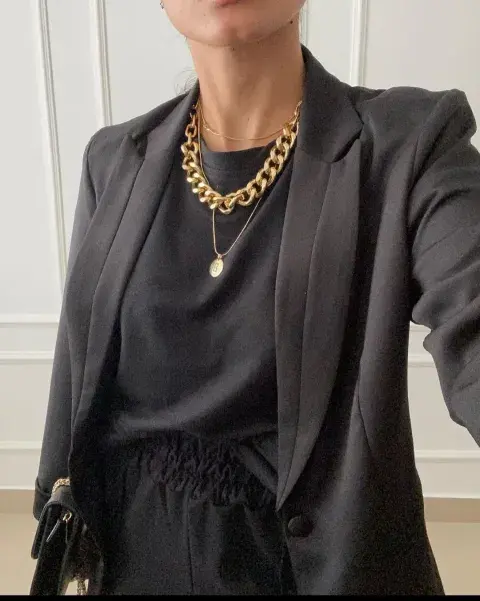 Una mujer con un total black y accesorios en dorado Una mujer con un total black y accesorios en dorado