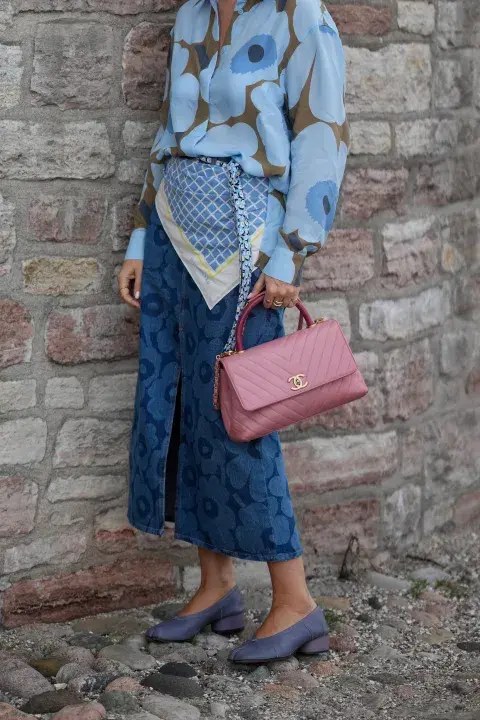 Una mujer vestida con messycore un pañuelo en la cintura, jeans capri y camisa de flores Una mujer vestida con messycore un pañuelo en la cintura, jeans capri y camisa de flores