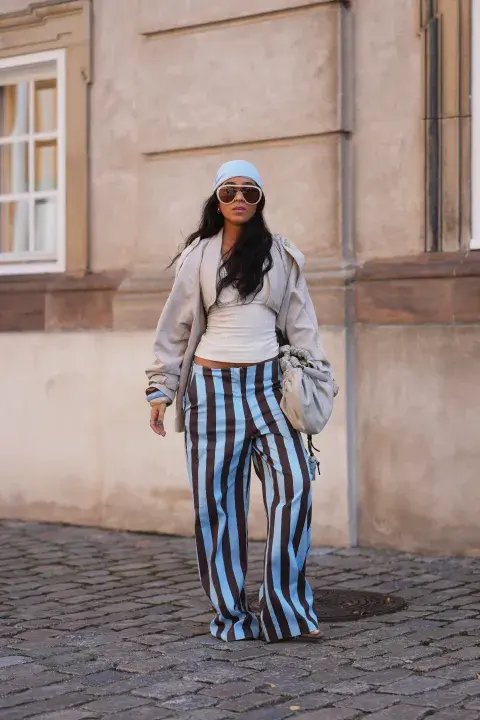 Una mujer con un pantalón a rayas, lentes xl y una bandana en la cabeza Una mujer con un pantalón a rayas, lentes xl y una bandana en la cabeza