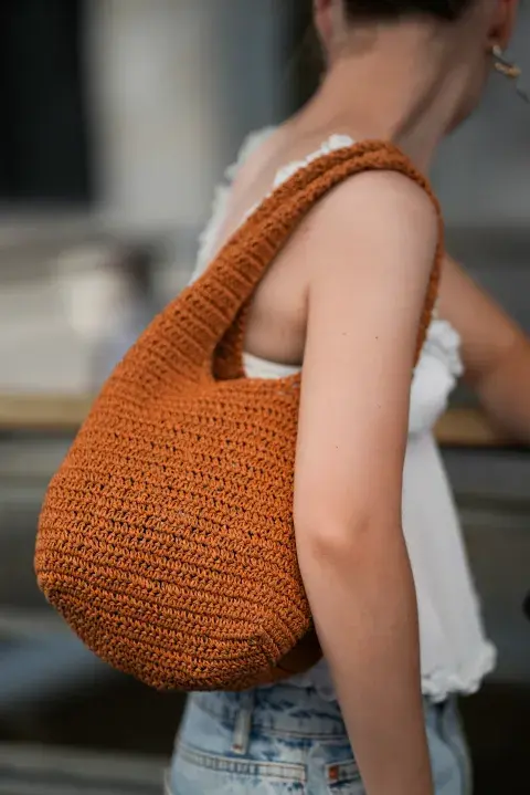 Una mujer con una cartera de rafia en color naranja Una mujer con una cartera de rafia en color naranja