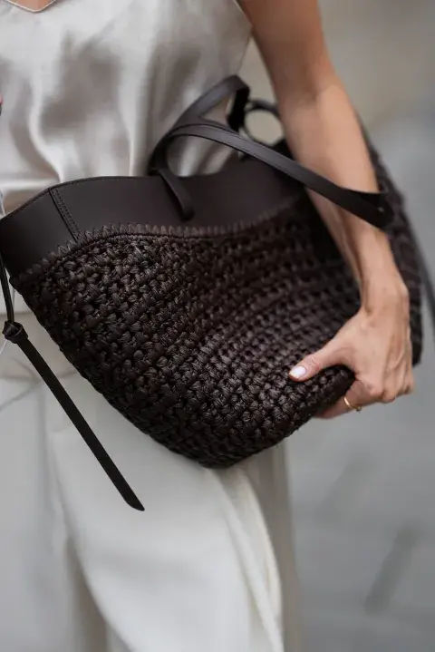 Una mujer con una cartera de rafia en color negro Una mujer con una cartera de rafia en color negro