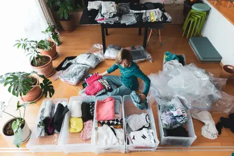 Una mujer ordenando la ropa en cajas Una mujer ordenando la ropa en cajas