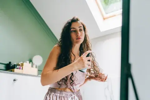 Una mujer con rulos peinandose Una mujer con rulos peinandose