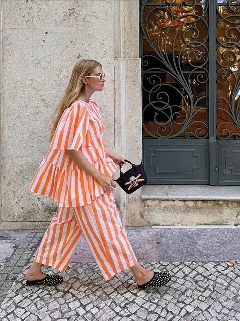 Una mujer caminando con un conjunto de rayas de color naranja y blanco Una mujer caminando con un conjunto de rayas de color naranja y blanco
