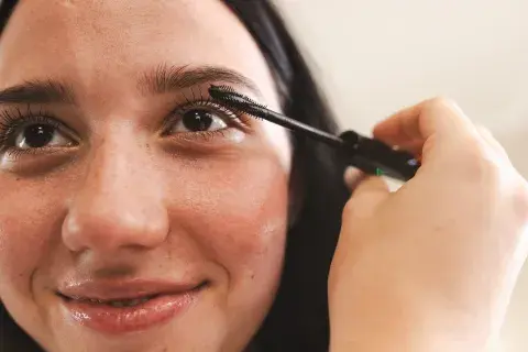 Una mujer con una máscara de pestañas pintándose los ojos Una mujer con una máscara de pestañas pintándose los ojos
