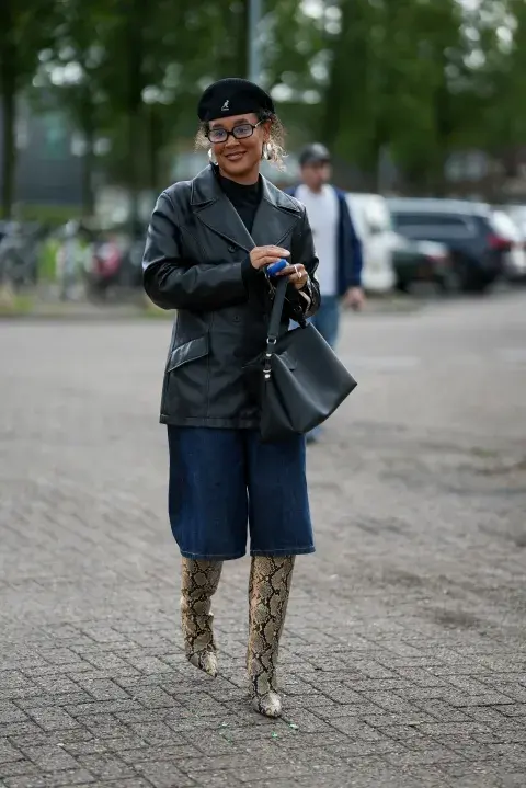 Una mujer en Amsterdam fashion week con un look de street style con un pantalón de jean pescador y botas xl