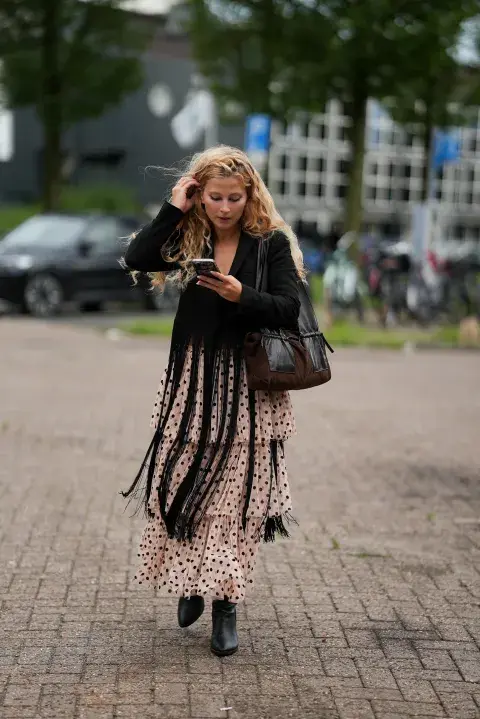 Una mujer en Amsterdam fashion week con un look de street style con una maxifalda con lunares en color negro 