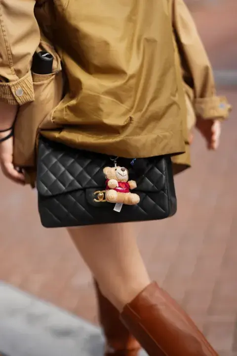 Una mujer en Amsterdam fashion week con un look de street style con una cartera con un charm de un oso colgando
