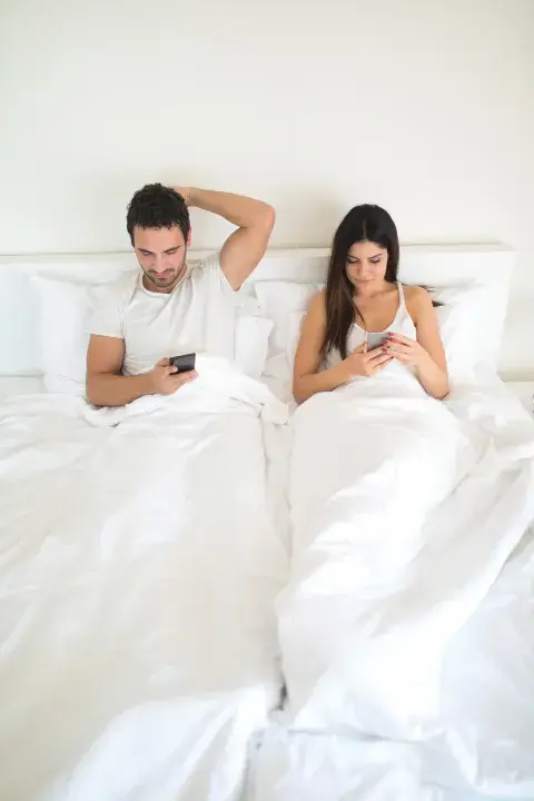 pareja en cama con celulares pareja en cama con celulares