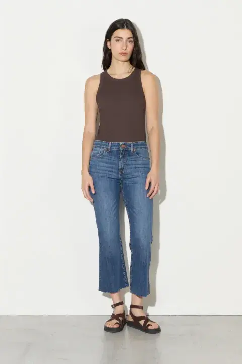 Una mujer usando un jean cropped gastado con sandalias negras Una mujer usando un jean cropped gastado con sandalias negras
