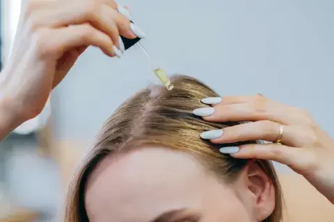 Foto de mujer apliçándose un aceite en el cabello. Foto de mujer apliçándose un aceite en el cabello.