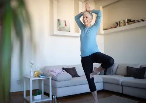 Mujer madura haciendo ejercicio de yoga en casa