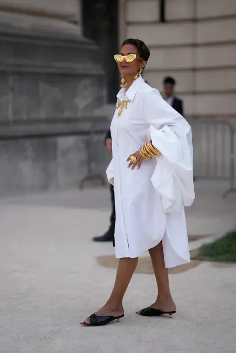 Una mujer caminando por parís fashion week con accesorios en color dorado