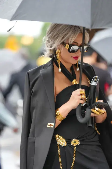 Una mujer caminando por parís fashion week con accesorios en color dorado