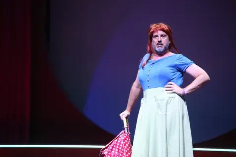 Juan Pablo Geretto vestido de mujer con una peluca y un changuito de compras. Juan Pablo Geretto vestido de mujer con una peluca y un changuito de compras.