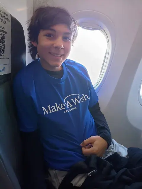 Niño sentado dentro de un avión, al lado de la ventana.