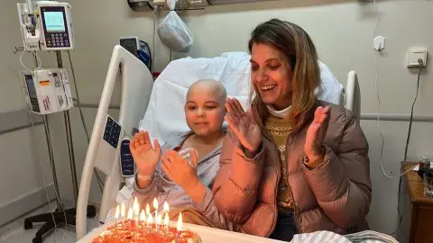 niño con enfermedad terminal y su mamá soplando las velitas en el clínica