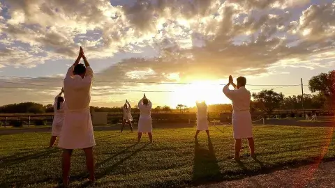 Unas personas en bata haciendo yoga al aire libre.