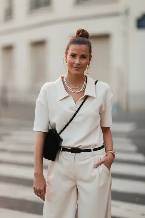 Una mujer con un conjunto en color crema y accesorios en negro Una mujer con un conjunto en color crema y accesorios en negro