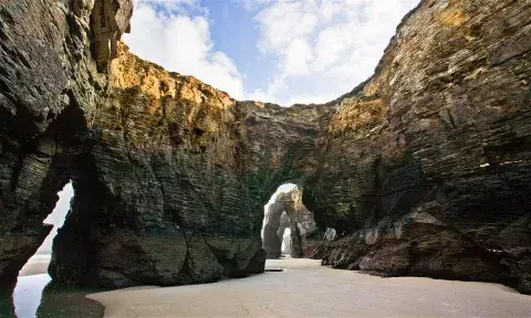 La palya de Las Catedrales, en un extremo de Galicia, es conocida por grandes arcos cavados en las rocas por el mar a lo largo de millones de años