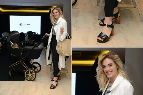 Emilia Attias, con una camisola blanca, pantalones negros con lazo, remera a rayas y sandalias negras con pulsera, en un evento de los cochecitos Cybex