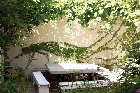 La mesa de concreto de lados irregulares, con bancos del mismo material, le dan al patio un toque moderno La mesa de concreto de lados irregulares, con bancos del mismo material, le dan al patio un toque moderno