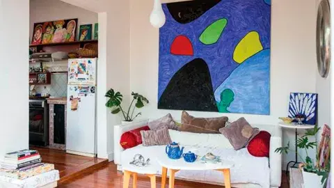 Sillón cubierto de almohadones de terciopelo, mesita alta heredada con obra de su madre, mesa ratona oval (Woodmarket) y Lámparas gota (Red Sur) Sillón cubierto de almohadones de terciopelo, mesita alta heredada con obra de su madre, mesa ratona oval (Woodmarket) y Lámparas gota (Red Sur)