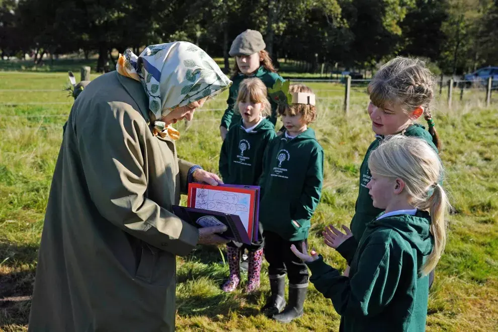 Los niños de la escuela primaria Crathie le presentan a la reina Isabel II de Gran Bretaña una tarjeta después de que la reina y el príncipe Carlos, príncipe de Gales de Gran Bretaña, plantaron un árbol para marcar el inicio de la temporada oficial de plantación del Queen's Green Canopy (QGC), en el Balmoral Cricket Pavilion , Balmoral Estate en Escocia, el 1 de octubre de 2021