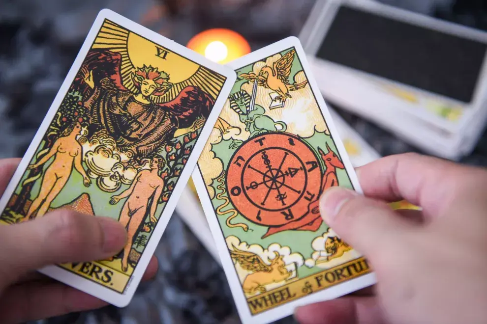 Dos cartas de tarot sostenidas por una mano.