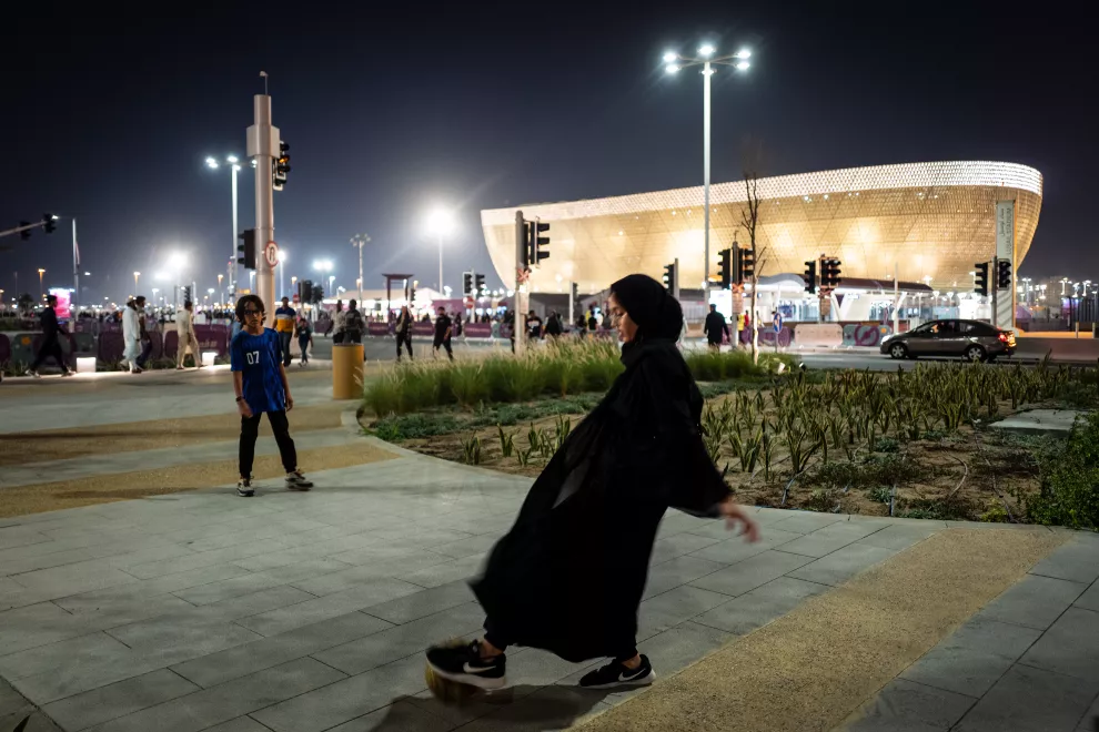 Qatar: un varón y una nena juegan a la pelota en las inmediaciones de un estadio.