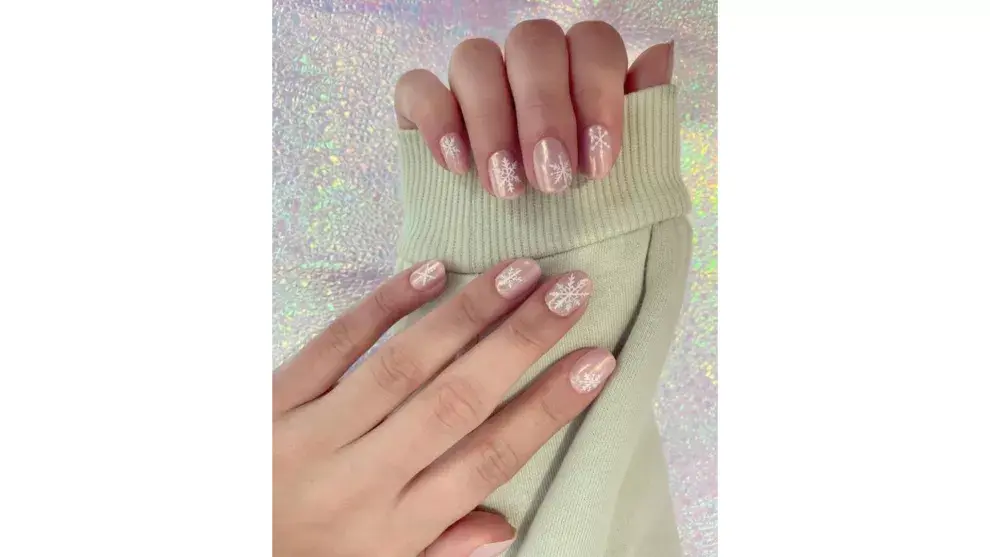 uñas rosa pastel con copos de nieve blancos