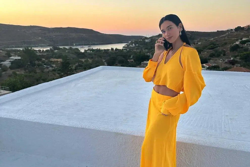 Dua Lipa con crop top de manga larga y aberturas en los hombros y una maxi falda en conjunto
