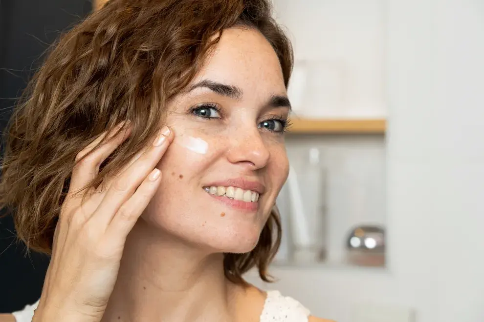 Mujer colocándose crema hidratante.