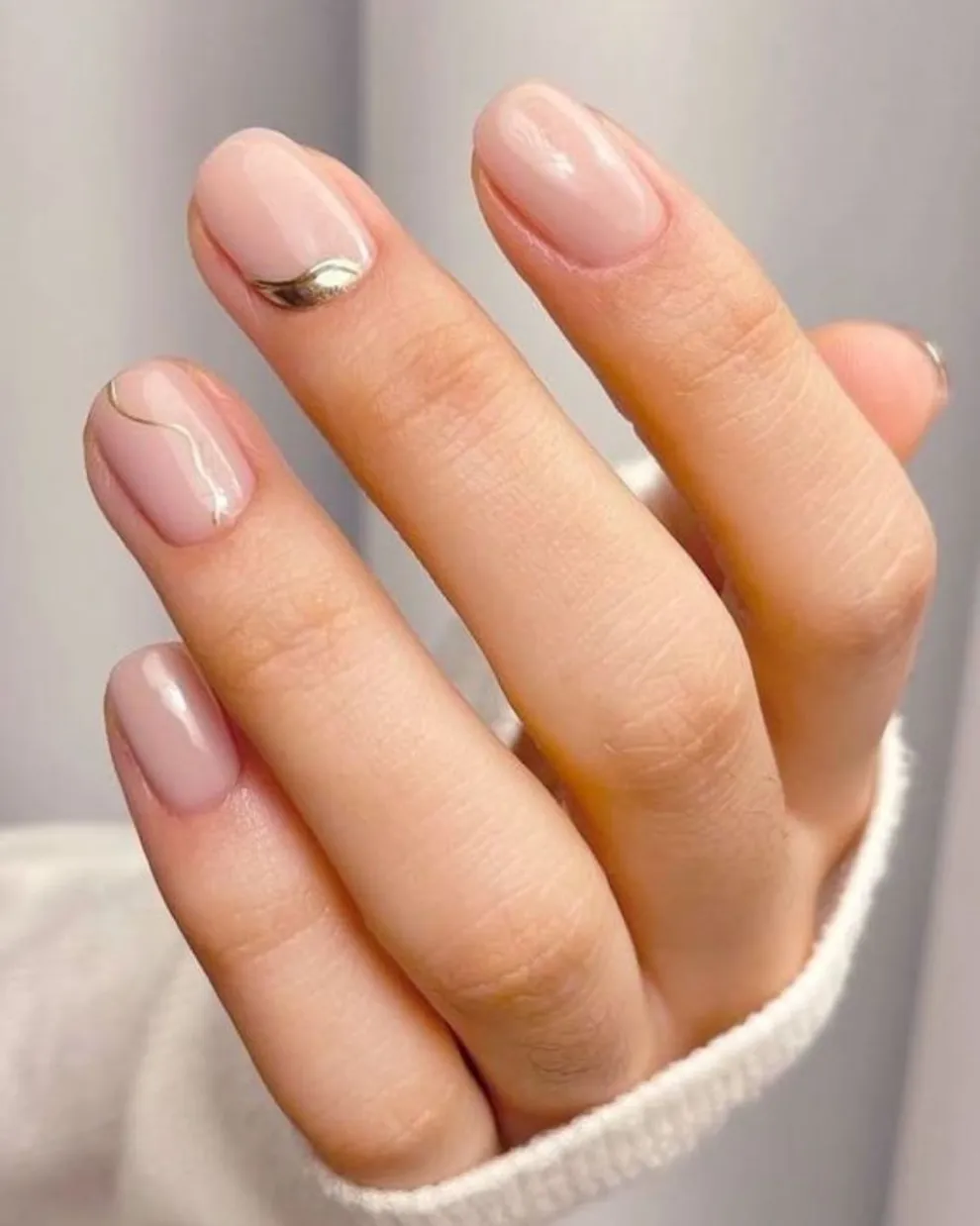 También es una re opción combinar las milky nails con diseños no lineales en color dorado o plateado.