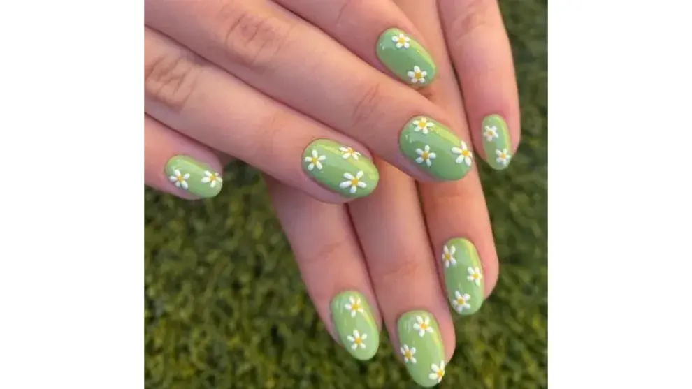 Diseño para uñas con margaritas blancas sobre un fondo verde pastel