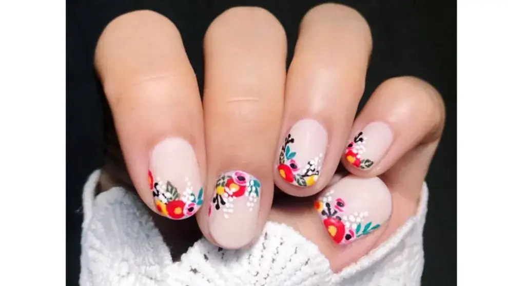Nail art de flores rojas, rosas y blancas con hojas en distintos tonos de verde