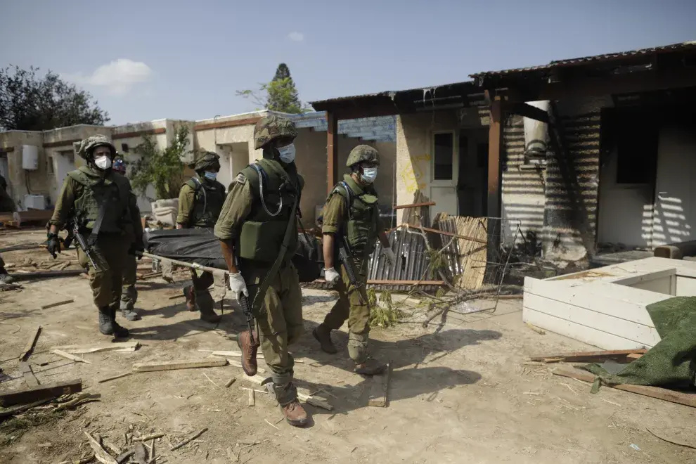 Soldados israelíes retiran el cuerpo de un civil asesinado en este kibutz cerca de la frontera con Gaza, en Kfar Aza.