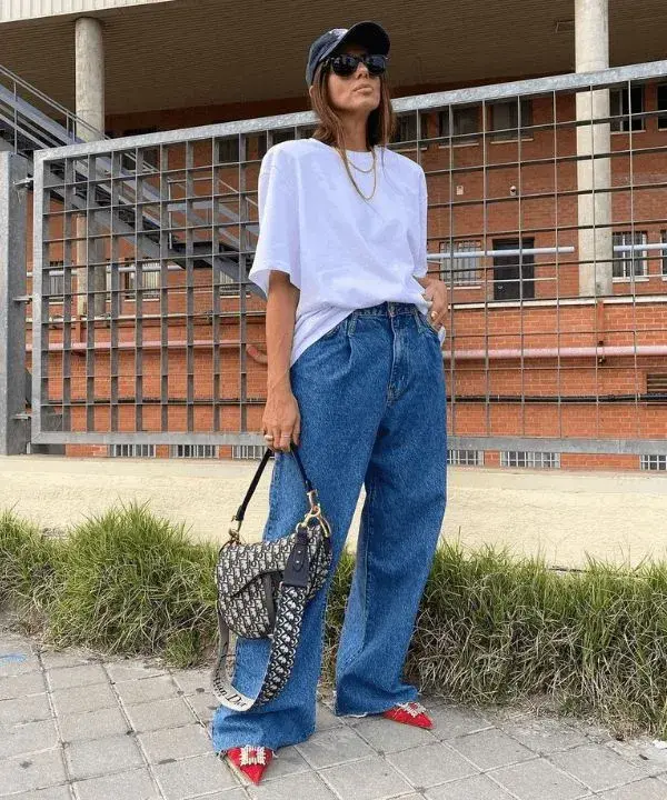 Remera blanca oversize con jean ancho y estilettos.