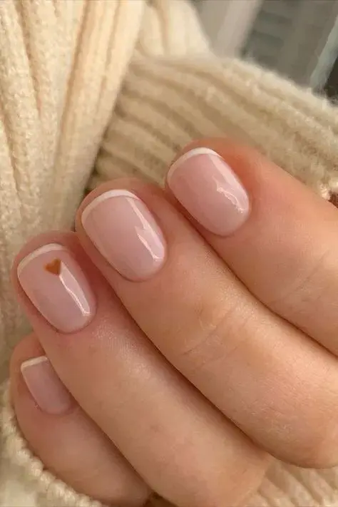 Este nail art agrega el detalle de un corazón en una de las uñas. Es fácil de hacer en casa y le da un toque distinto al baby french clásico.