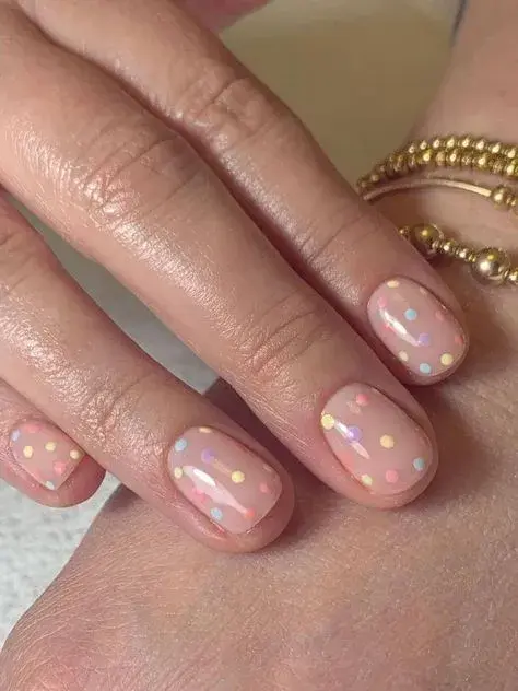 También con base de esmalte transparente pero con varios puntos en distintos colores pastel, otra de las tendencias de "nail art" en esta temporada.