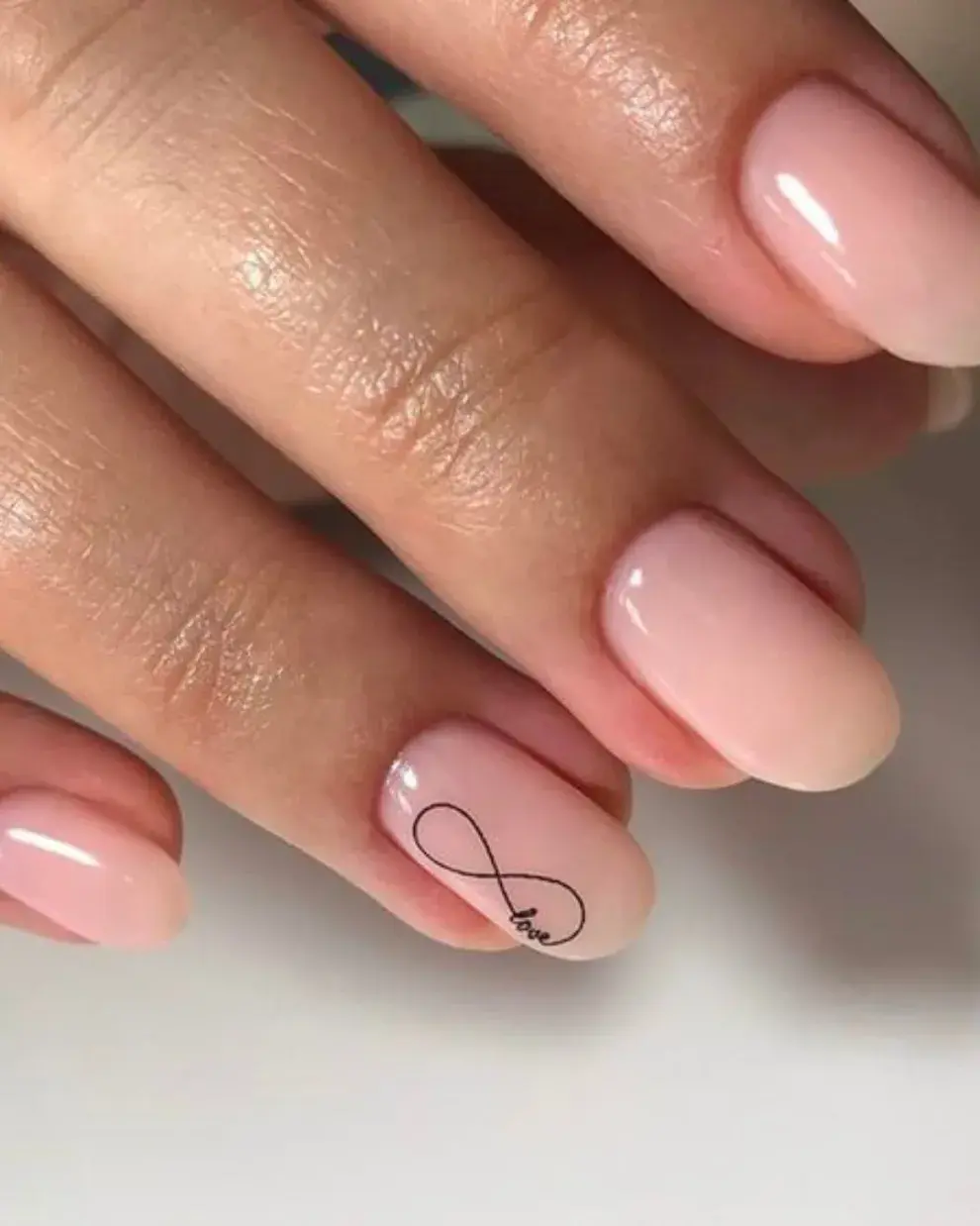 Sobre un esmalte rosa pálido, un dibujo en negro en solo una de las uñas.