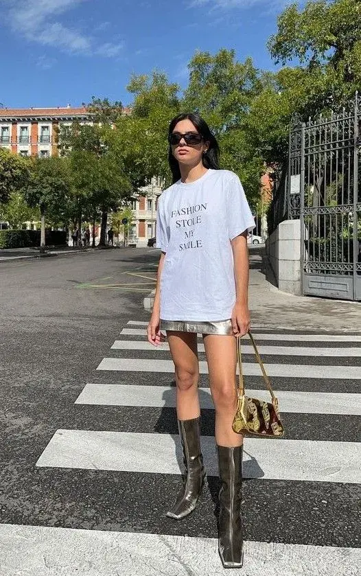 Remera blanca con estampa oversize con mini y botas altas.