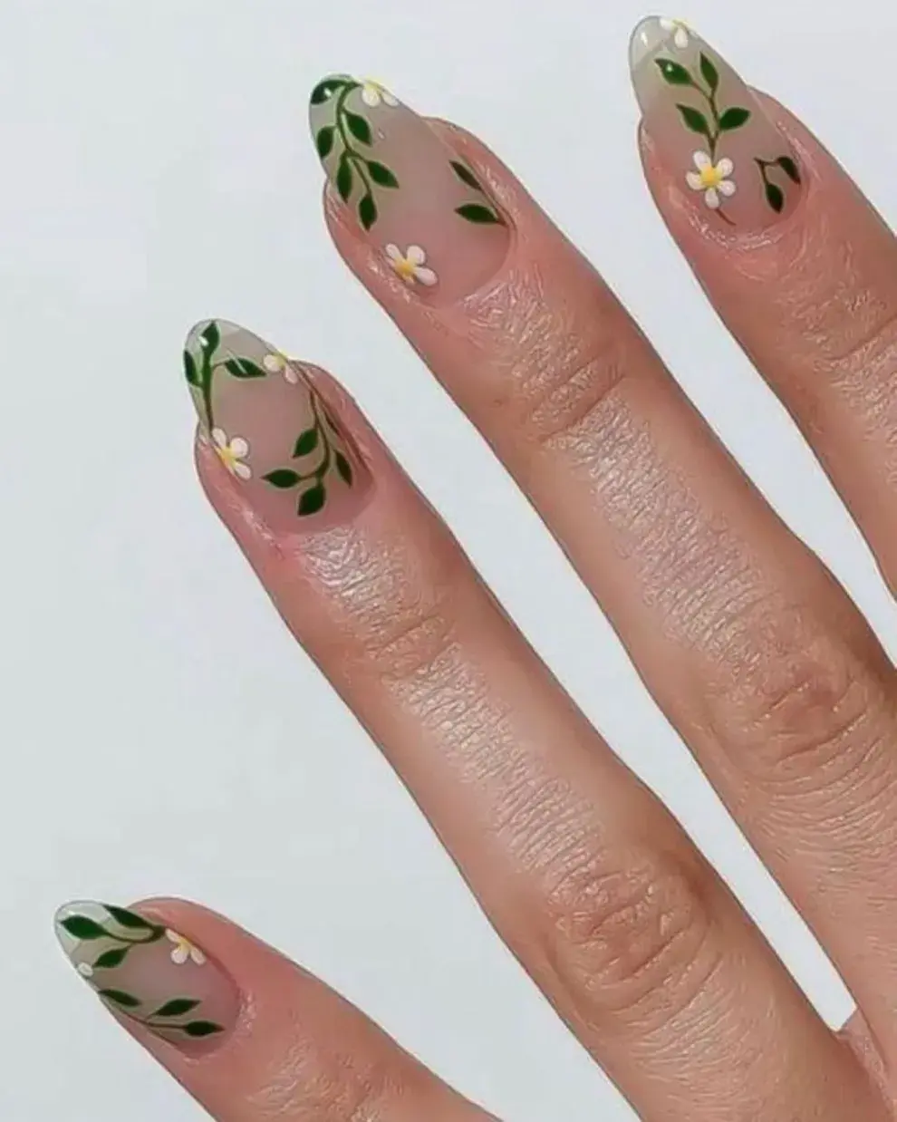 Sobre un esmalte transparente, un diseñito de plantas en verde, blanco y amarillo.